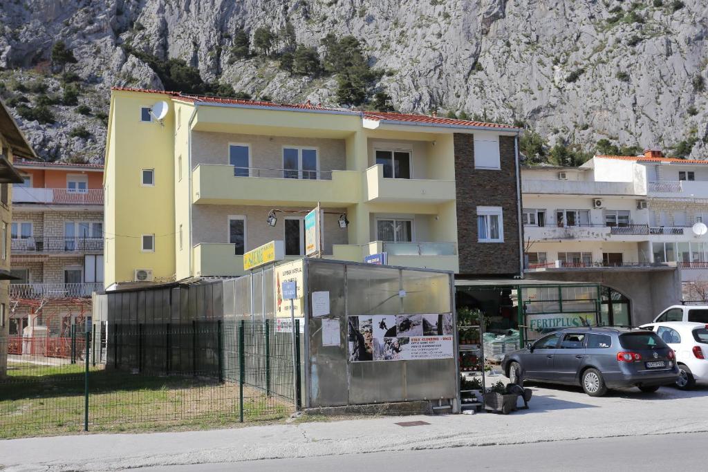 un edificio amarillo junto a un aparcamiento con coches en Apartments with a parking space Omis - 10362, en Omiš