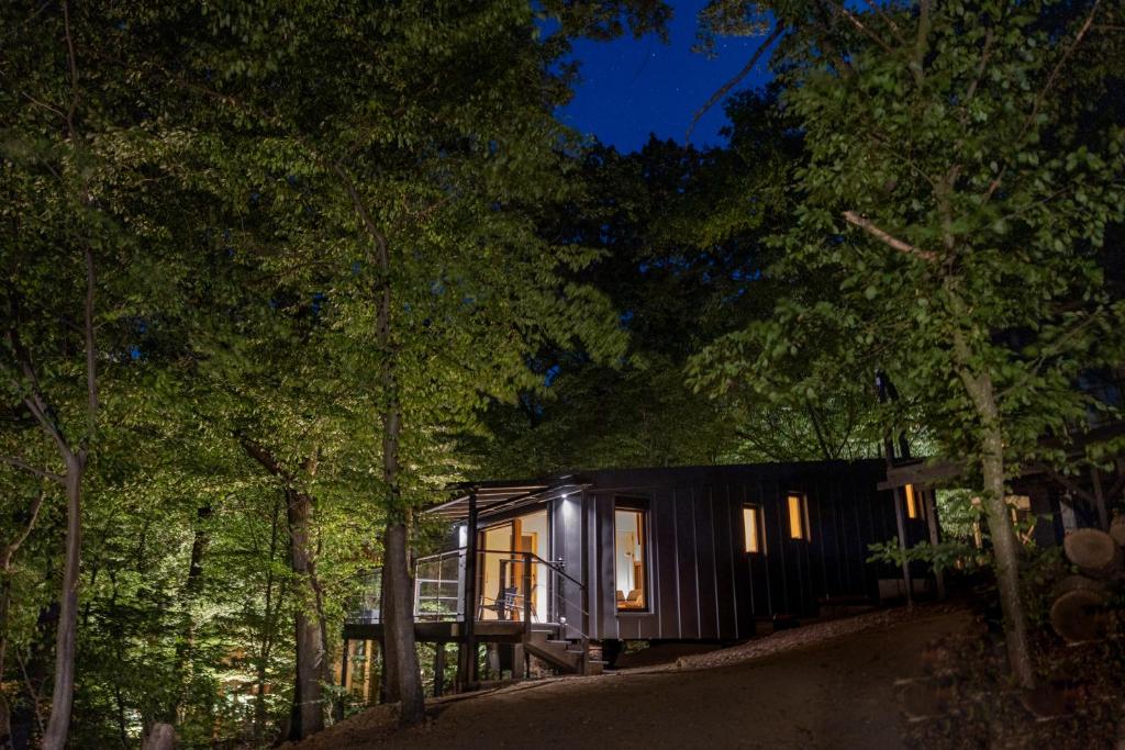 una pequeña cabaña negra en el bosque por la noche en Nomád Glamping, en Noszvaj