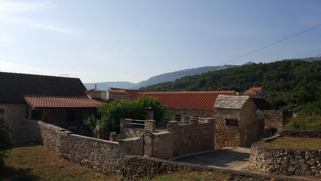 een groep gebouwen met bergen op de achtergrond bij Holiday house with a swimming pool Vrbanj, Hvar - 11040 in Vrbanj