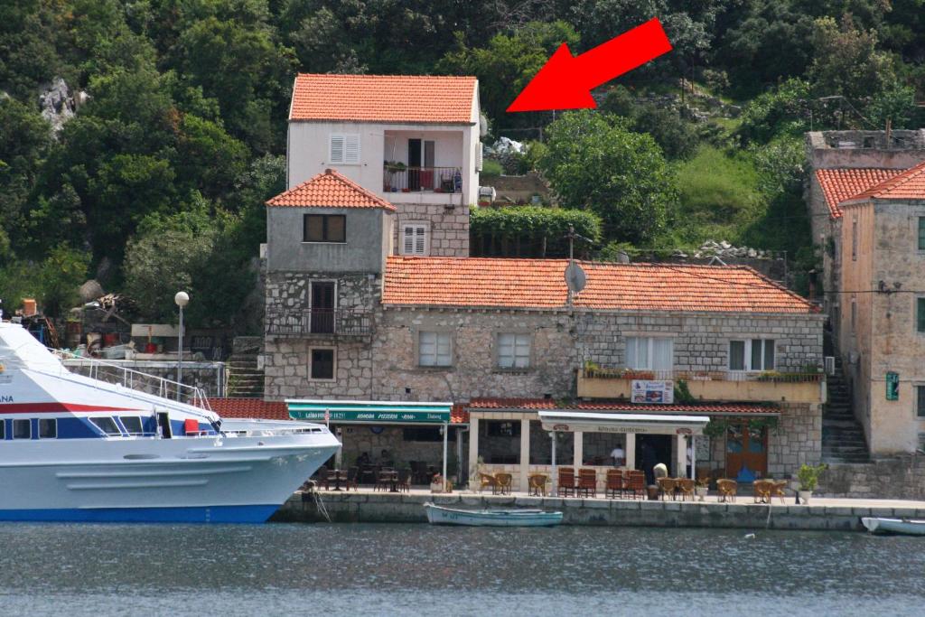 ein Boot, das neben einem Gebäude mit einem roten Pfeil angedockt ist in der Unterkunft Apartments by the sea Sobra, Mljet - 11011 in Sobra