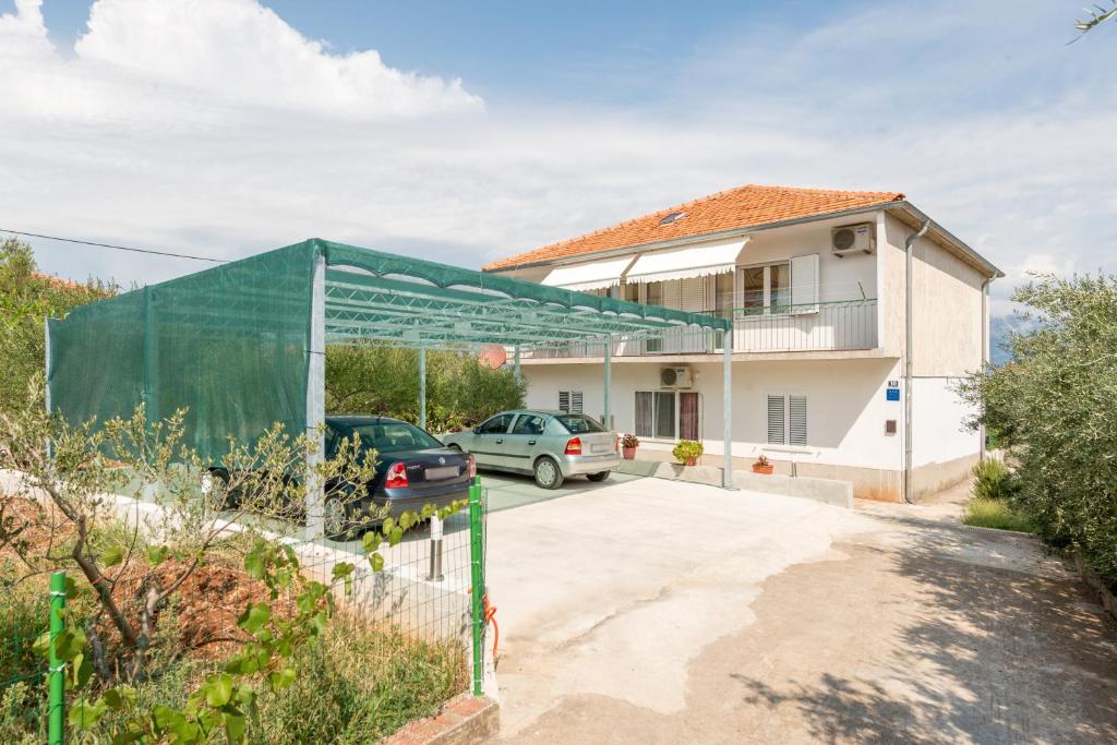 ein Haus mit einer grünen Abdeckung vor einer Einfahrt in der Unterkunft Apartments by the sea Slatine, Ciovo - 11047 in Slatine