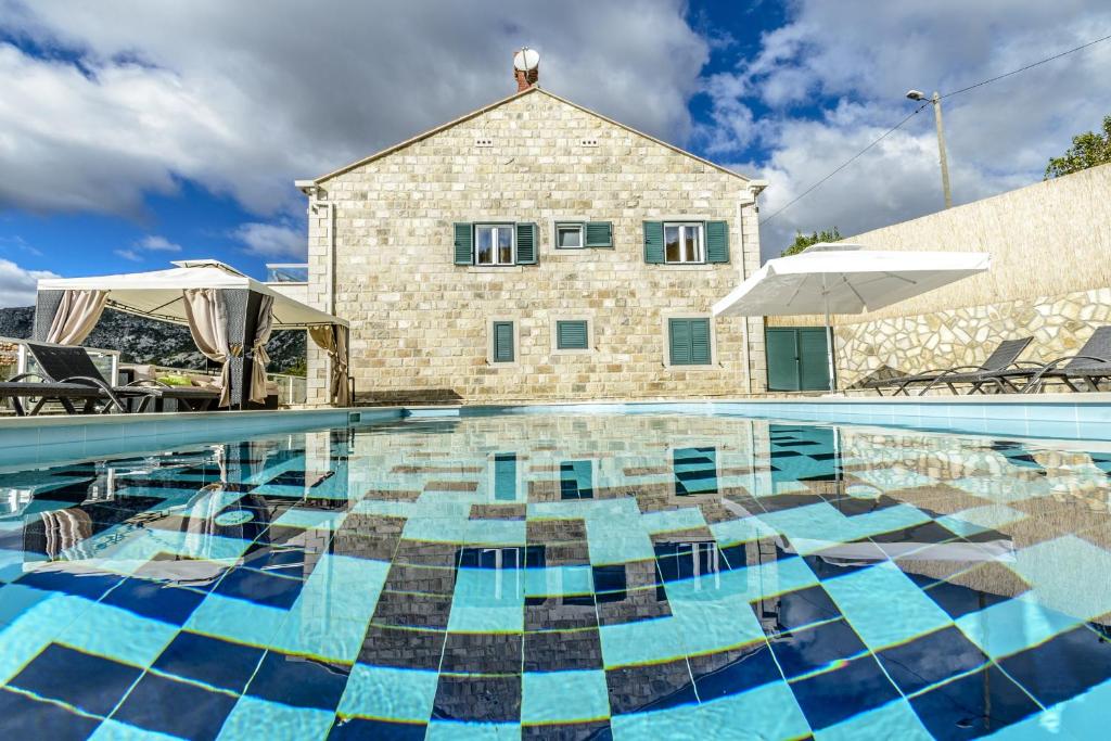 a swimming pool with a house in the background at Luxury villa with a swimming pool Dubravka, Dubrovnik - 11073 in Gruda