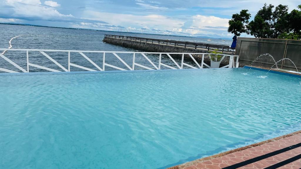 a large blue swimming pool next to a body of water at Lola's Guest House in Mactan