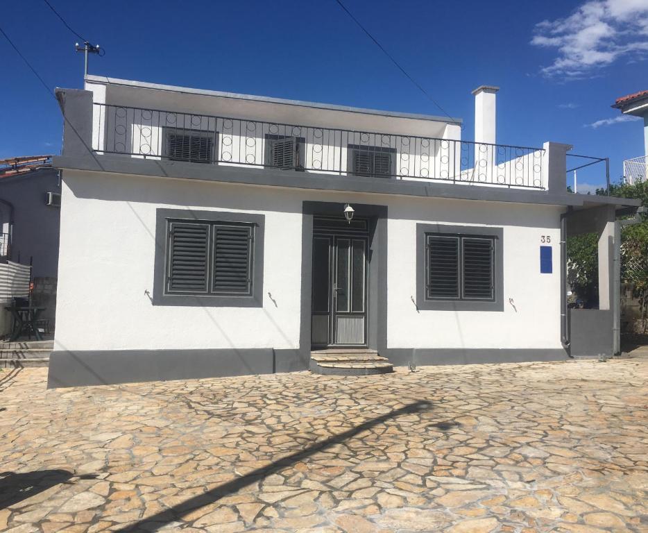 a white house with a door and a balcony at Rooms with a parking space Selce, Crikvenica - 11133 in Selce