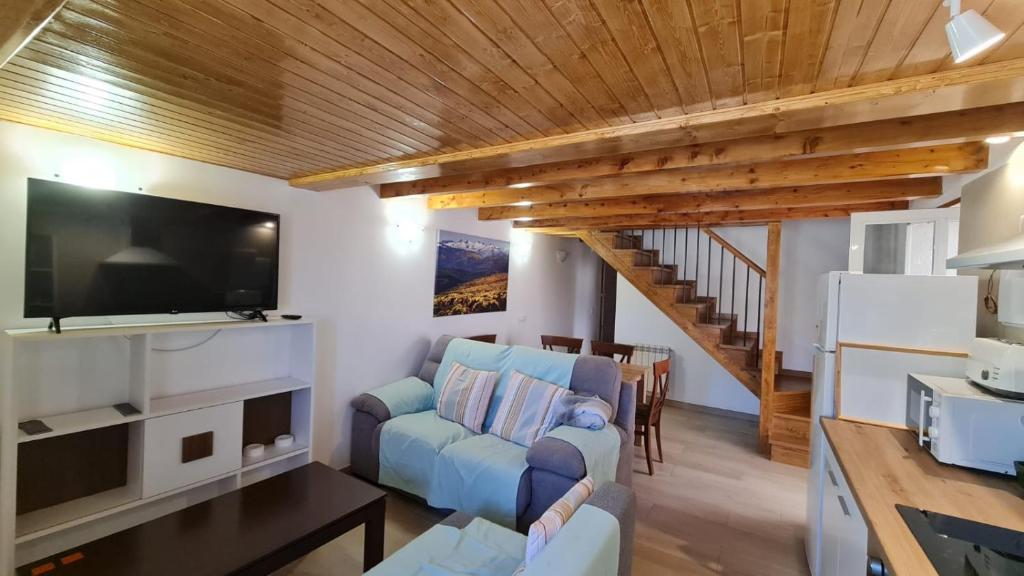 uma sala de estar com um sofá e uma televisão de ecrã plano em Casa rural los 7 pinos de Gredos em Navarredonda de Gredos