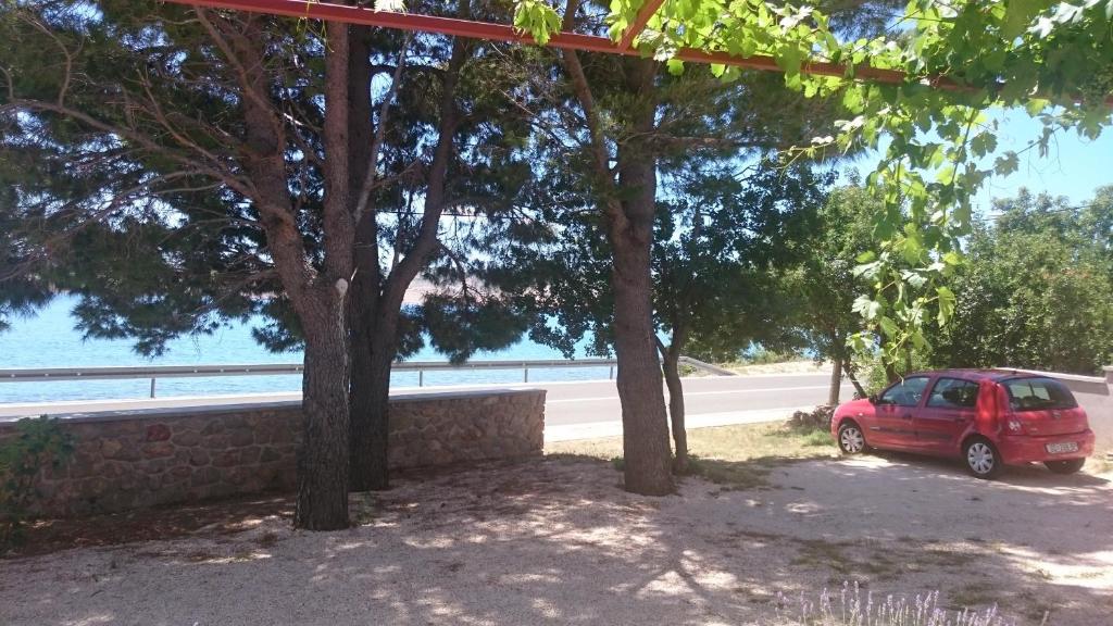 a red car parked under trees next to a road at Apartment Seline 11197b in Starigrad