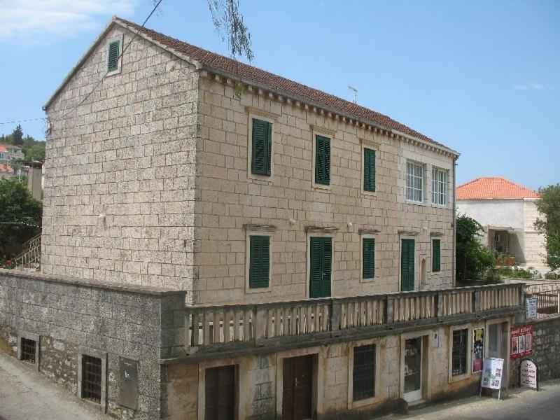an old brick building with green shutters on a street at Apartments by the sea Lumbarda, Korcula - 11275 in Lumbarda