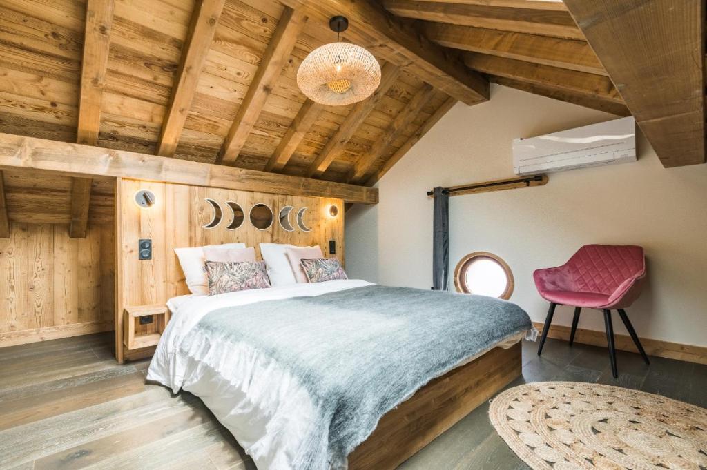 ein Schlafzimmer mit einem großen Bett und einem rosa Stuhl in der Unterkunft La Grange à Roger in Myans