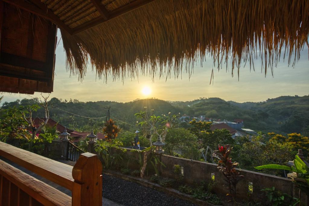 - une vue sur le coucher du soleil depuis une cabane avec un banc dans l'établissement Alit Cottage, à Nusa Penida