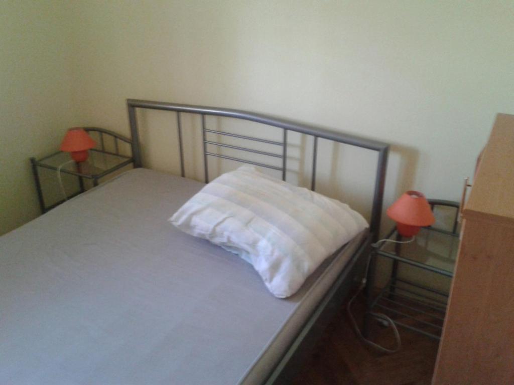 a bed with a white pillow on it with two lamps at Apartments with a parking space Betina, Murter - 11322 in Betina