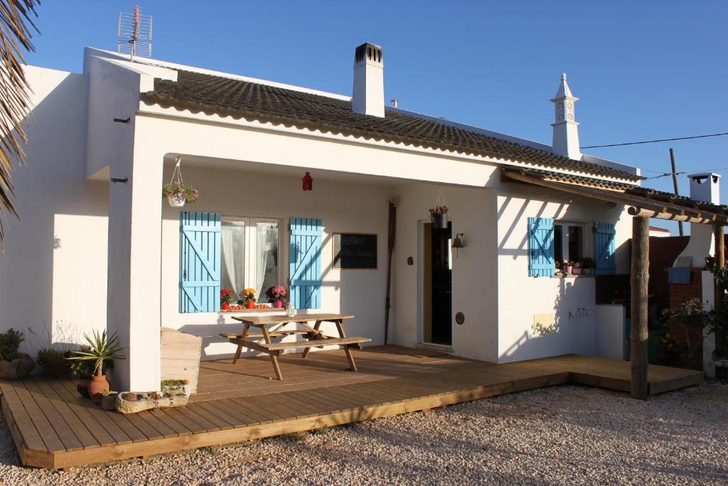 een klein wit huis met een houten terras bij PuraVida Divehouse in Sagres