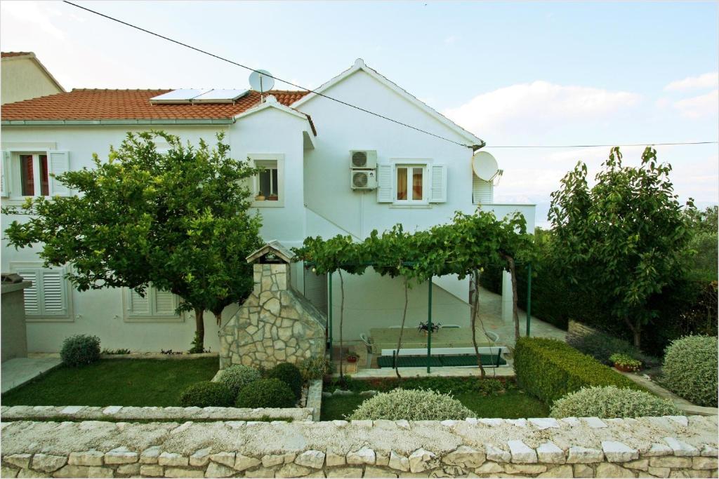 une maison blanche avec un banc dans la cour dans l'établissement Apartments with a parking space Supetar, Brac - 11147, à Supetar