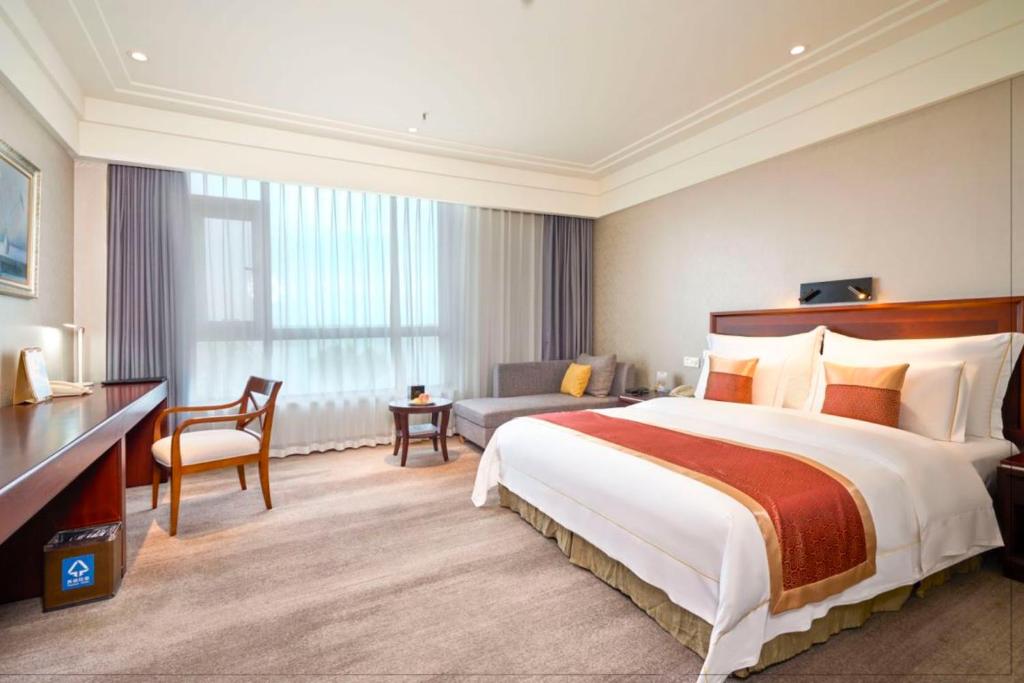 a large hotel room with a large bed and a chair at Tongli Lake View Hotel in Suzhou