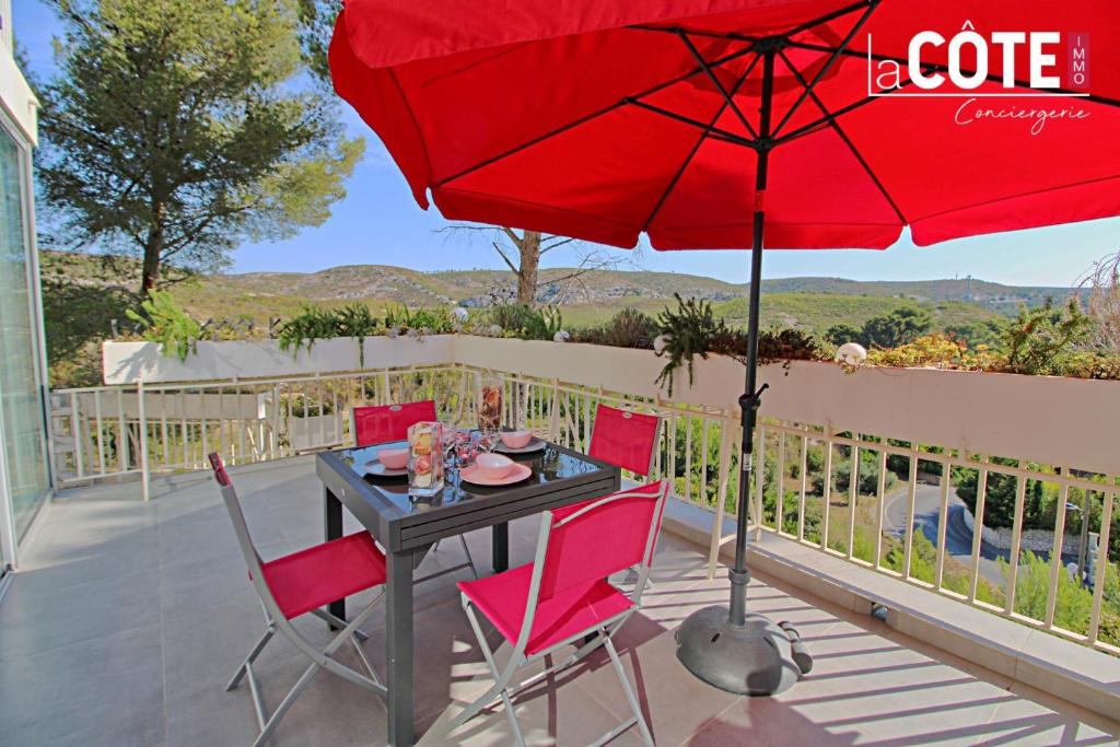 einen Tisch und Stühle mit einem roten Regenschirm auf einer Terrasse in der Unterkunft La Sourcinette T3 sur la côte Bleue Lacote Immo 1 in Carry-le-Rouet