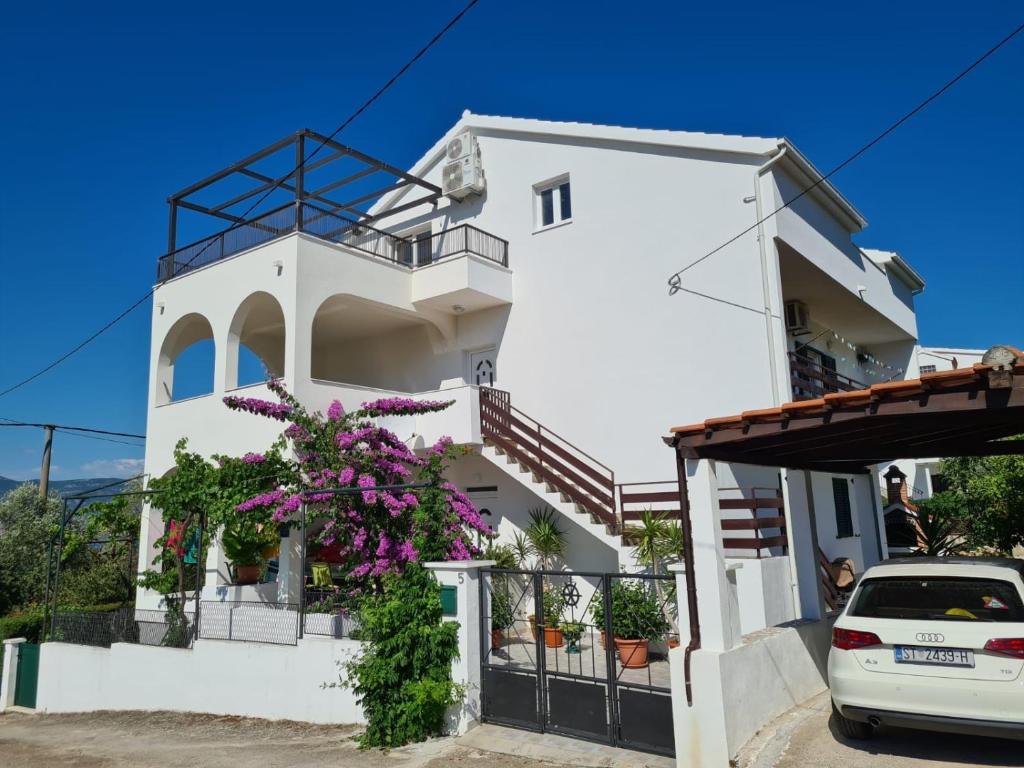 a white house with flowers in front of it at Apartments by the sea Arbanija, Ciovo - 11321 in Trogir