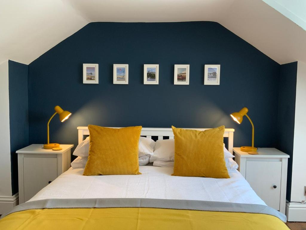um quarto azul com uma cama com almofadas amarelas em Charming Cottage mins from Chichester City Centre em Chichester