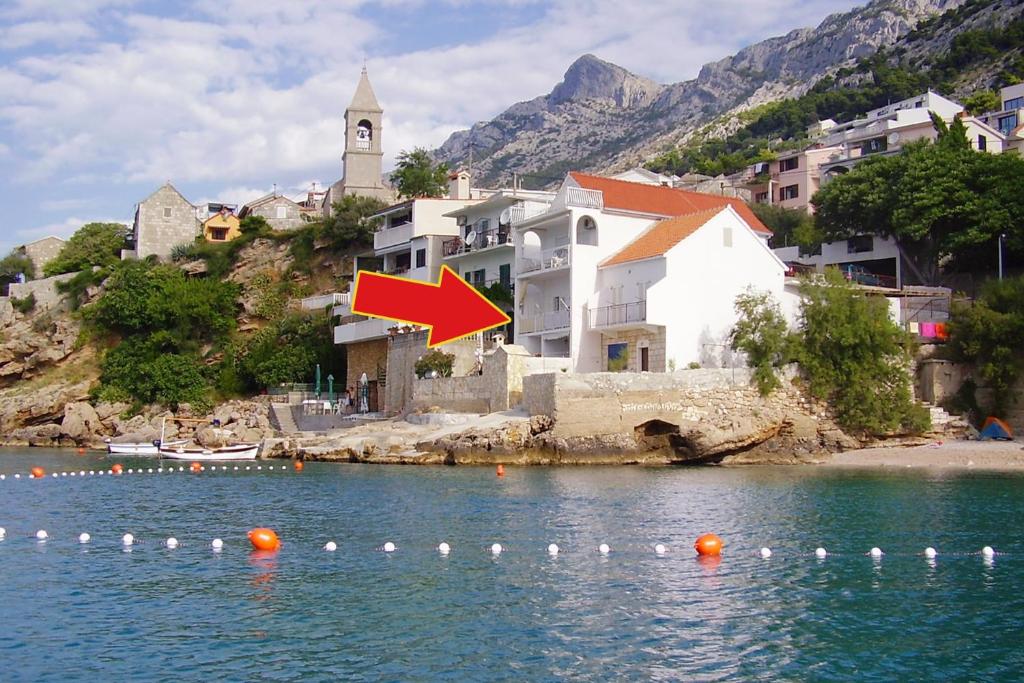 un grupo de edificios sobre el agua con una flecha roja en Apartments by the sea Pisak, Omis - 10410, en Mimice