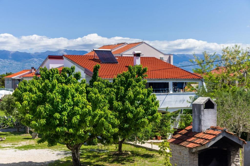 a house with a roof with a chimney and a tree at Apartments with a parking space Nin, Zadar - 10414 in Nin