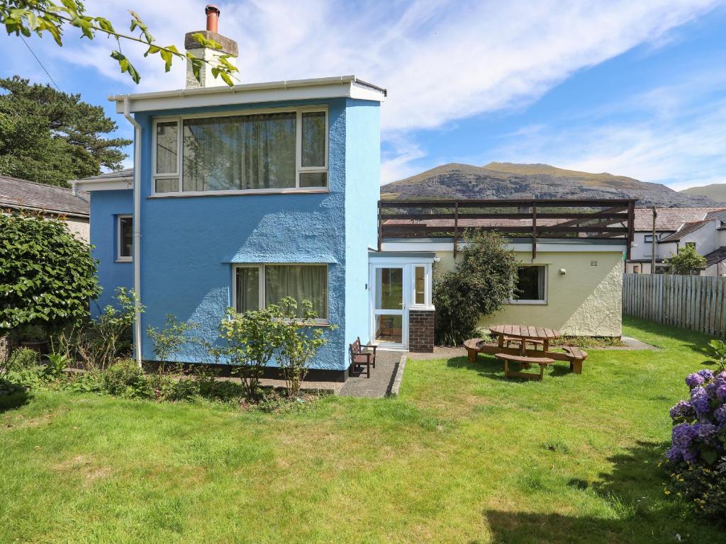 ein blaues Haus mit einem Picknicktisch im Hof in der Unterkunft Maesteg - Llanberis in Caernarfon