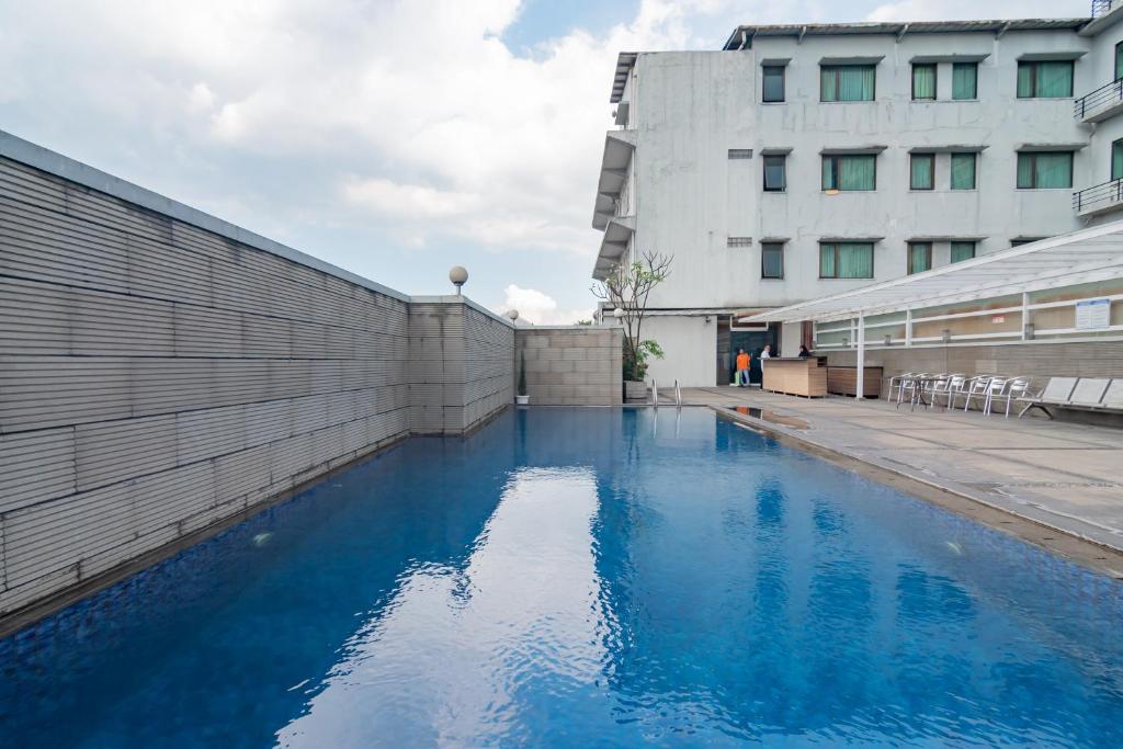 a pool of blue water next to a building at Urbanview Hotel Newton Riau Bandung by RedDoorz in Bandung