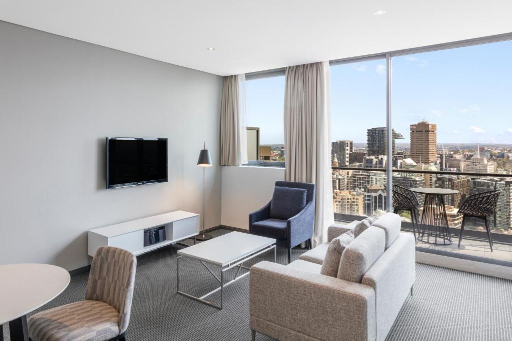 a living room with a view of a city at Meriton Suites Campbell Street, Sydney in Sydney