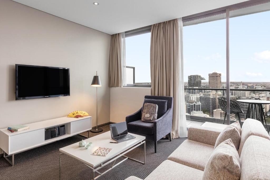 a living room with a couch and a tv at Meriton Suites Campbell Street, Sydney in Sydney