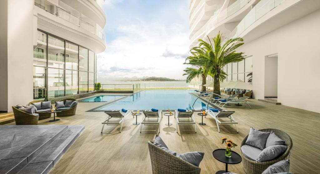 a pool in a building with chairs and a table at Citadines Marina Halong in Ha Long