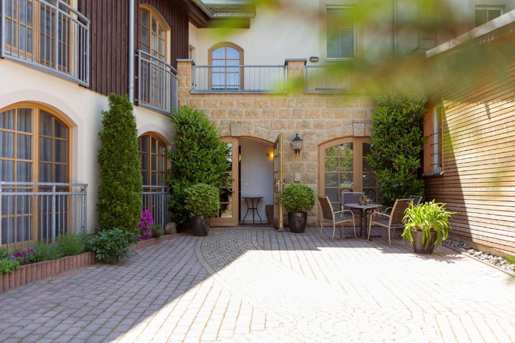 un patio de una casa con mesa y sillas en Hotel Ettrich & Elbresort Rathen, en Kurort Rathen