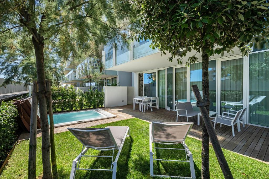 a garden with two chairs and a table in front of a building at Luxury Apartment Jesolo in Lido di Jesolo