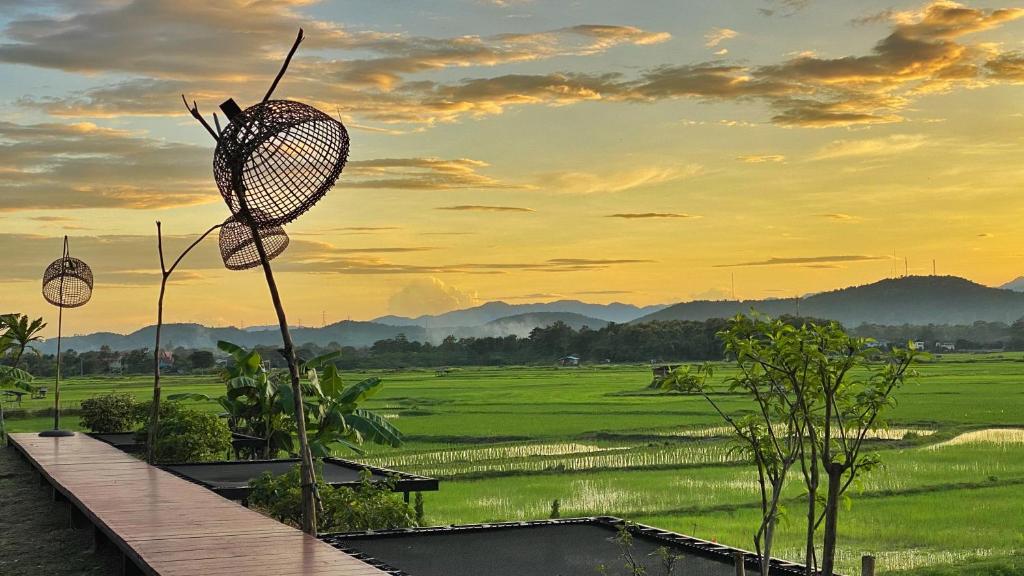 a view of a field at sunset with a net at Nan Seasons Boutique Resort in Nan