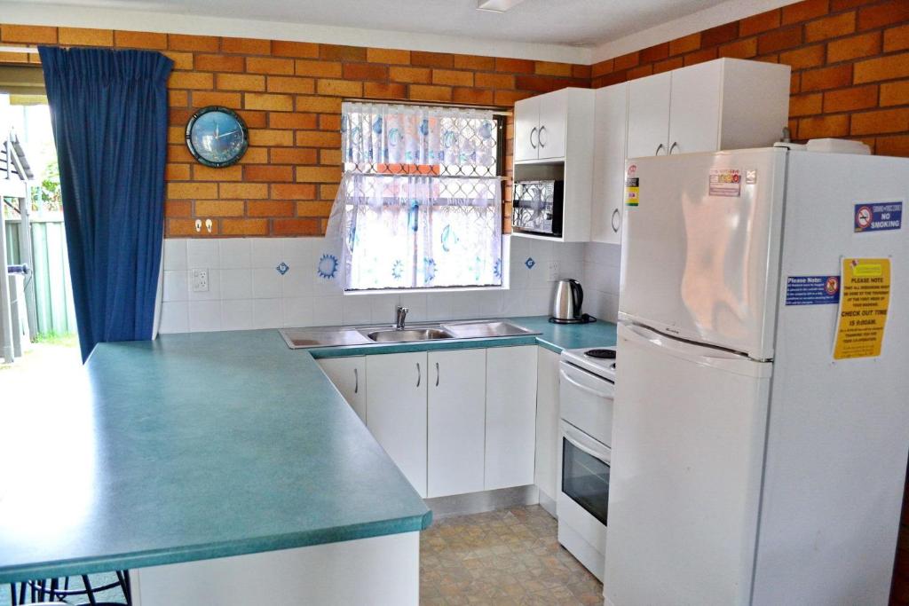 a kitchen with white cabinets and a refrigerator at Cameo Court 2 in South West Rocks