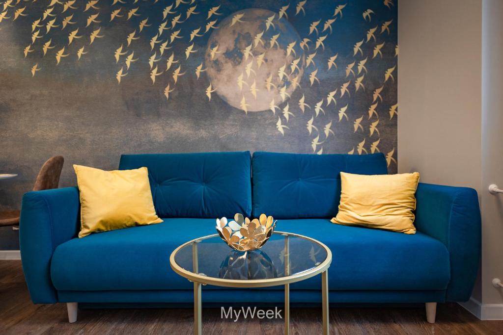 un canapé bleu avec des oreillers jaunes et une table en verre dans l'établissement Apartamenty Na Szlaku, MyWeek, à Kłodzko