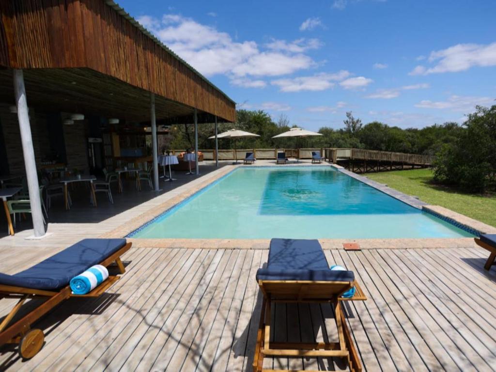 uma piscina com duas espreguiçadeiras e uma mesa em Kruger Safari Lodge em Reserva Manyeleti