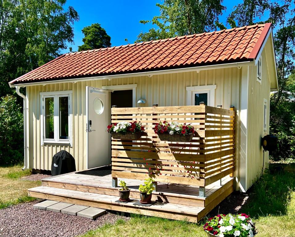 ein kleiner Schuppen mit einer Holzterrasse mit Blumen in der Unterkunft Bittes & Lasses Guest House in Kalmar
