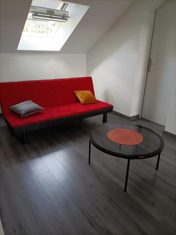 a red couch and a table in a room at La Ruelle : chambres d&#39;hôtes in Saumur