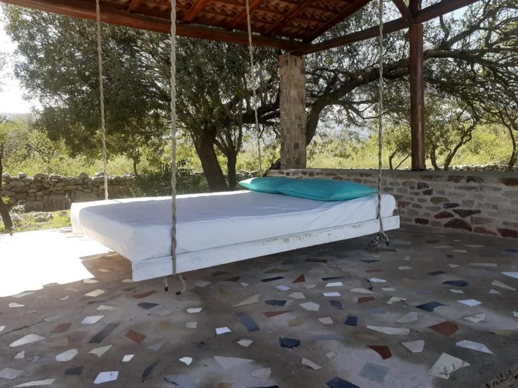 a swinging bed in a pavilion with a stone floor at Casitas de Campo in Mina Clavero