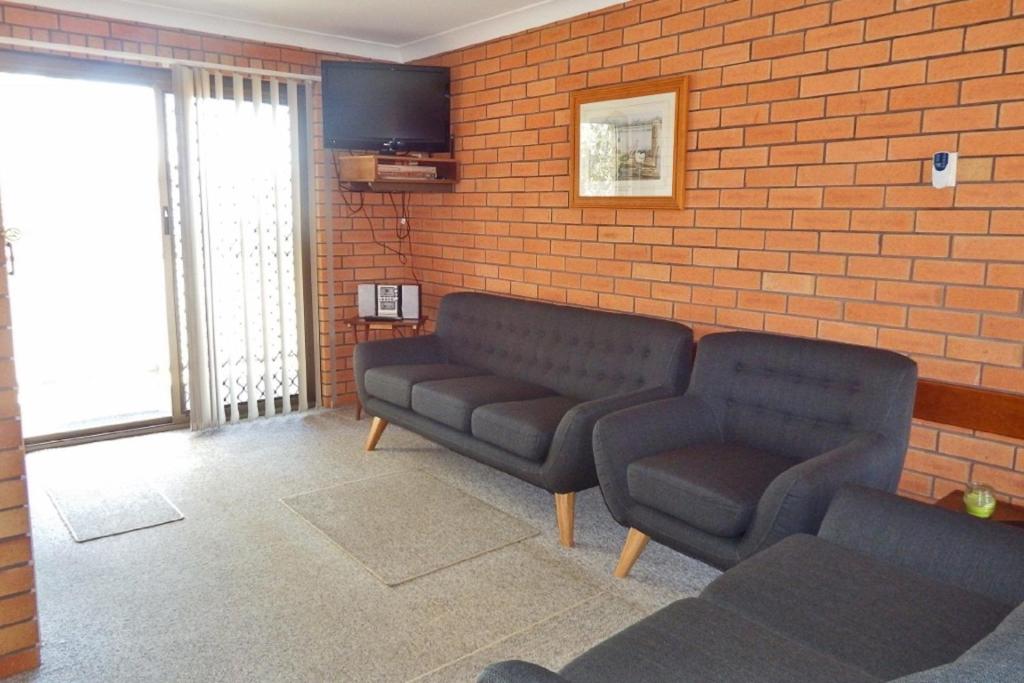 a waiting room with two couches and a brick wall at Cameo Court Unit 7 South West Rocks in South West Rocks