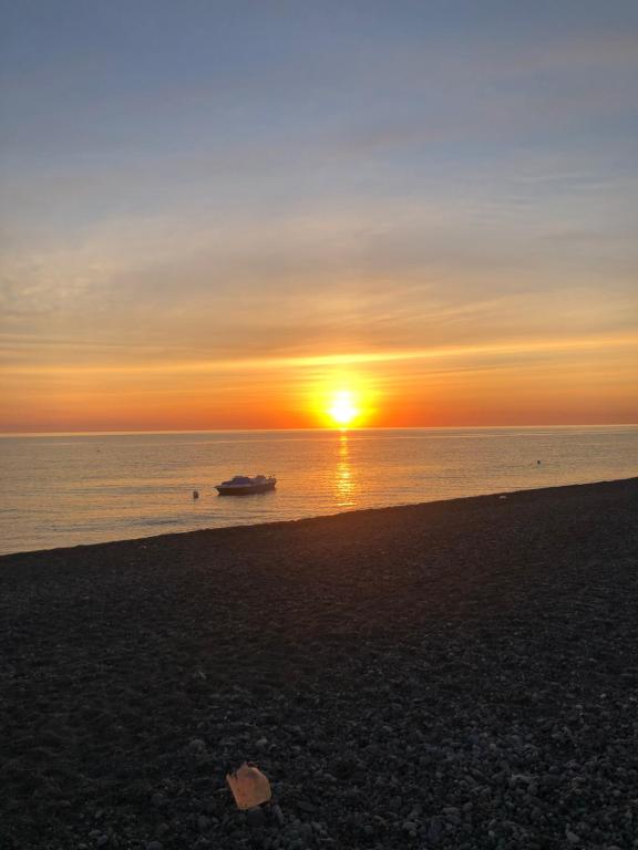 a sunset on the beach with a boat in the water at Brancaccio’s house summer in Paola