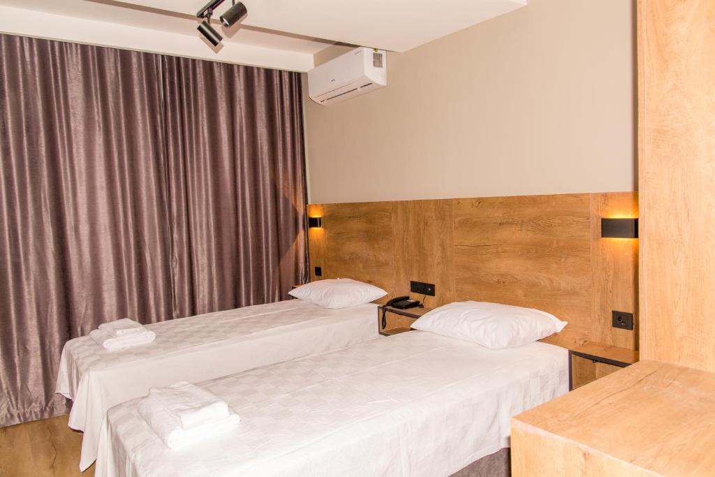 two beds in a hotel room with white sheets at Fidanoğlu Suite Hotel Çorlu in Çorlu