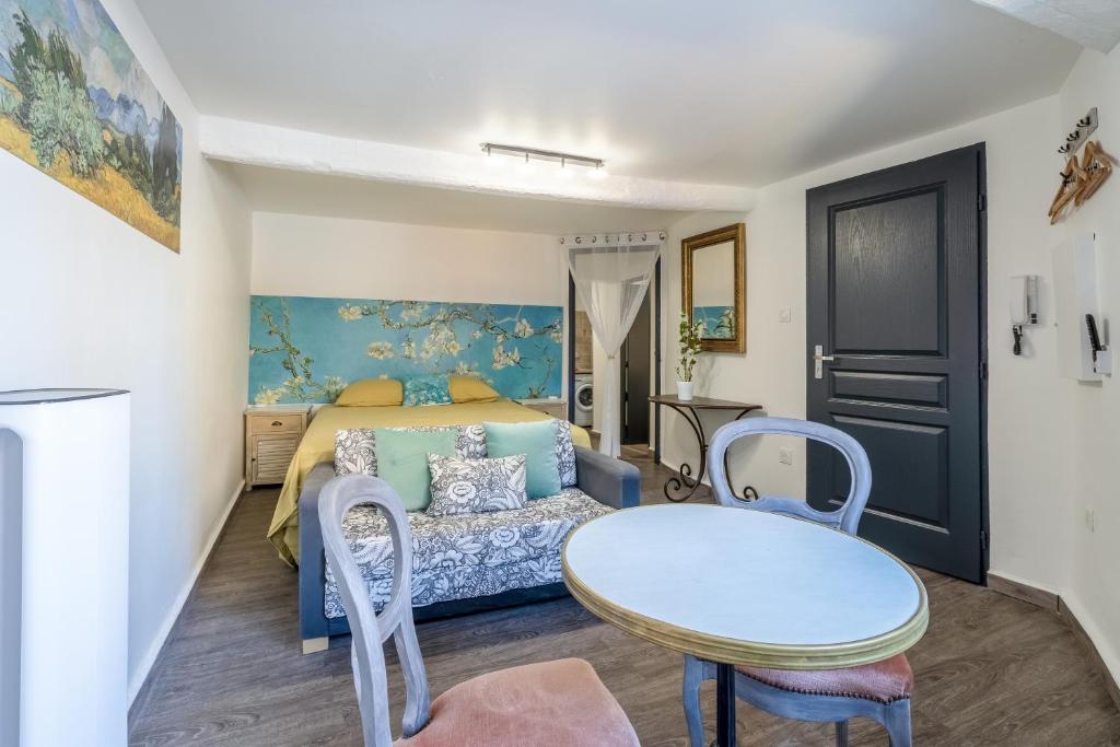 a bedroom with a bed and a table and chairs at L'ISLE D'OR - LES AMANDIERS - 3 étoiles - 1er étage in LʼIsle-sur-la-Sorgue