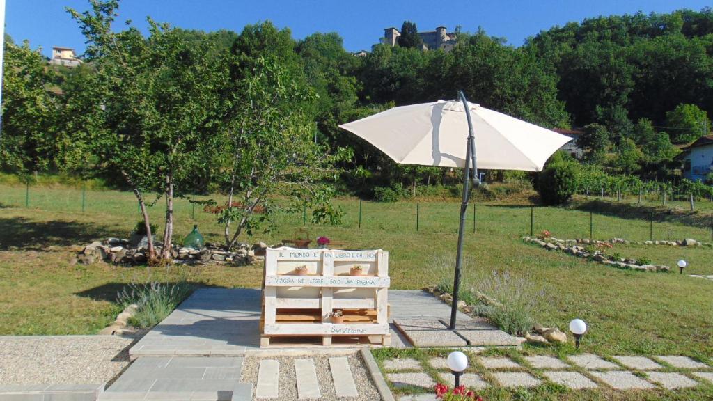 Monti di Licciana Nardi的住宿－Il Giardino di Marzo Guest House，一把白色的伞,坐在架子旁边,椅子