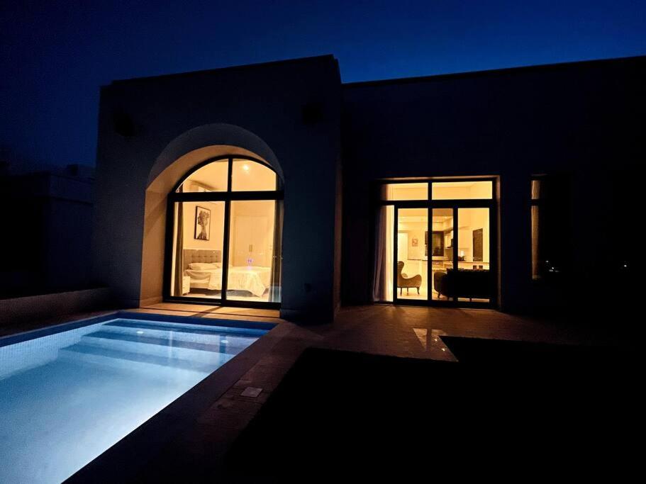 a swimming pool in front of a house at night at Hawana Lagoon Private villa with private pool in Salalah