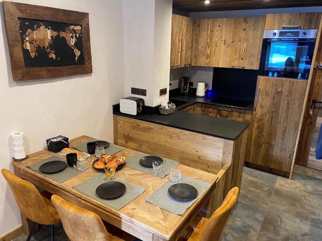 a kitchen with a wooden table with chairs and a counter at les jardins de val in Val-d'Isère