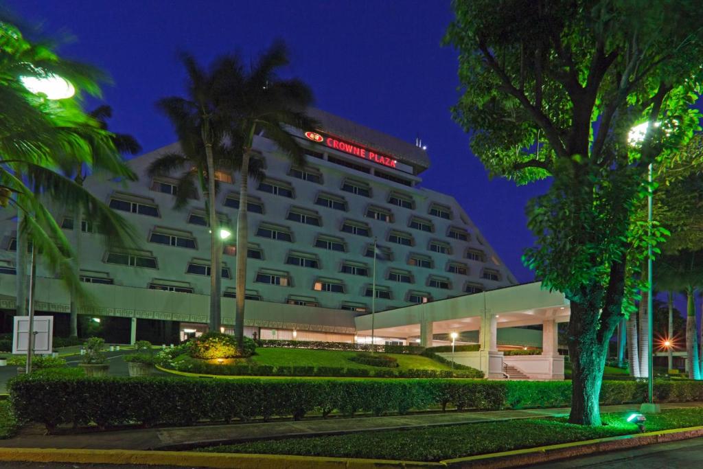 a large white building with palm trees in front of it at Crowne Plaza Managua, an IHG Hotel in Managua