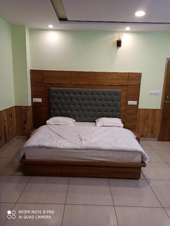 a bedroom with a large bed with a wooden headboard at CHAMAN BASERA in Shamshi