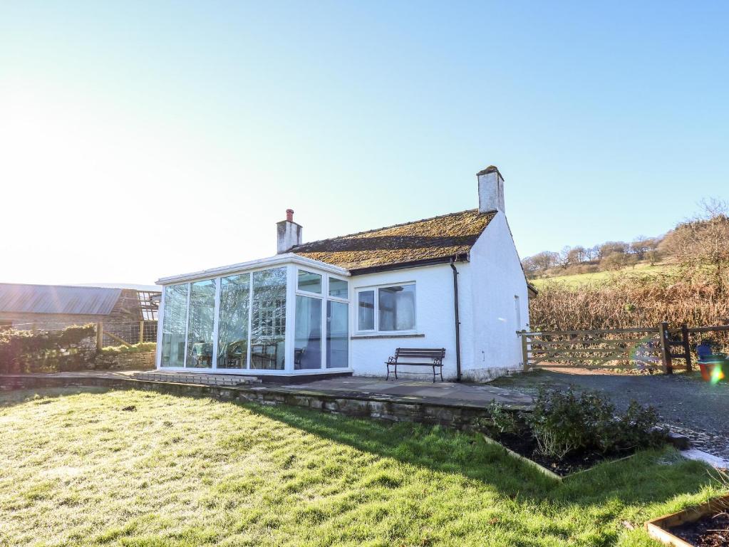 a small white cottage with glass doors on a yard at Ty Twmp Tump Cottage in Brecon