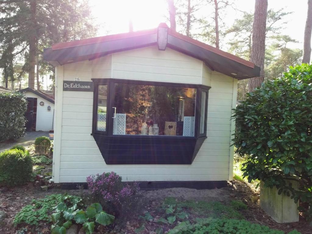 een klein huis met een raam in een tuin bij Chalet De Eekhoorn in Diever