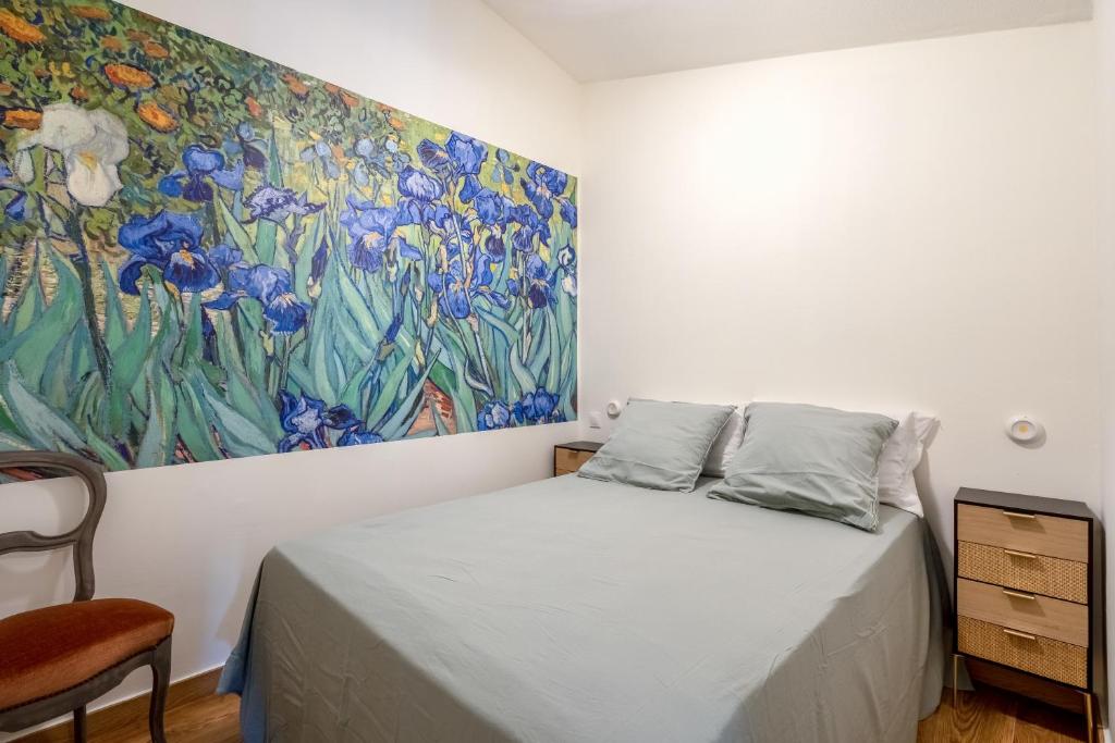 a bedroom with a painting on the wall next to a bed at L'IRIS D OR - 3 Étoiles- 3ème étage in LʼIsle-sur-la-Sorgue