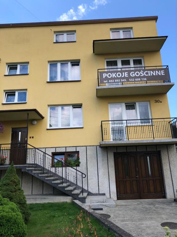 un edificio amarillo con un cartel que lee poco costuming en Pokoje Gościnne, en Skawina