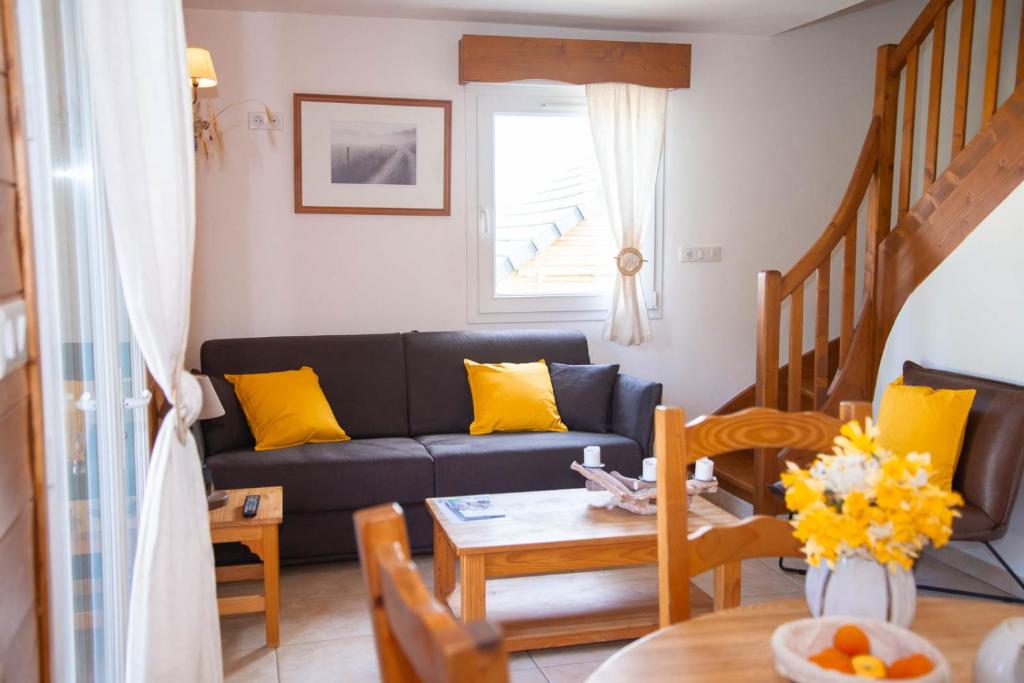 sala de estar con sofá negro y almohadas amarillas en Village de gîtes Les Chalets de l'Aubrac, en Aumont-Aubrac